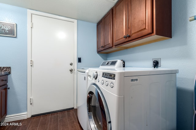 clothes washing area with washer and clothes dryer, cabinets, and a textured ceiling