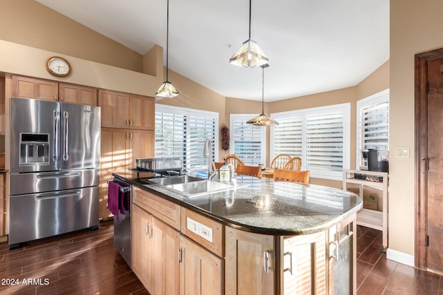 kitchen with pendant lighting, sink, stainless steel appliances, a center island with sink, and vaulted ceiling