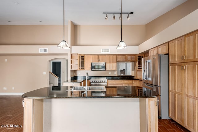 kitchen with a kitchen island with sink, premium appliances, and hanging light fixtures