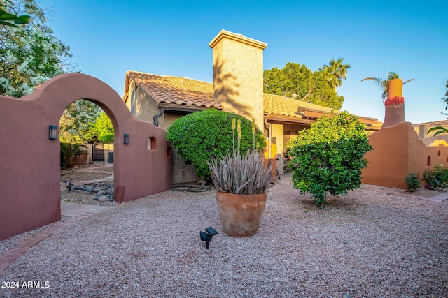 13128 N 104th Pl, Scottsdale, AZ 85260 - view of side of property with a chimney, a tile roof, stucco siding, and a gate