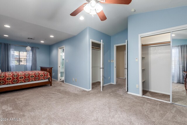 unfurnished bedroom featuring multiple closets, light colored carpet, and ceiling fan