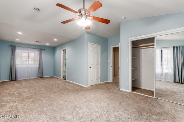 unfurnished bedroom with multiple windows, light colored carpet, and ceiling fan