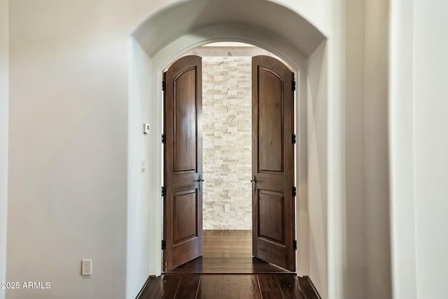 hall featuring arched walkways and dark wood-type flooring