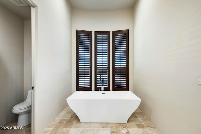 bathroom with toilet, visible vents, and a freestanding bath