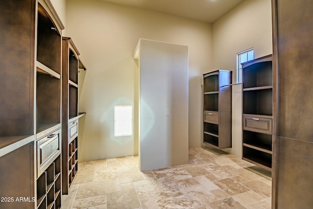 walk in closet with stone tile flooring