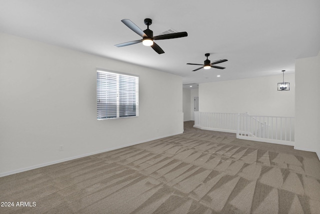 carpeted empty room featuring ceiling fan with notable chandelier