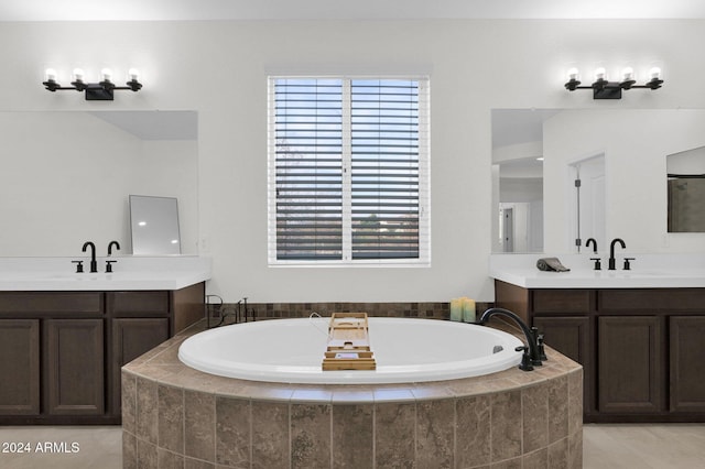 bathroom with tile patterned flooring, vanity, and a relaxing tiled tub