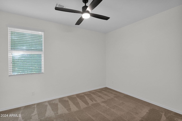 carpeted spare room featuring ceiling fan and a healthy amount of sunlight