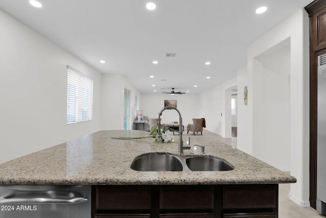 kitchen featuring ceiling fan, light stone countertops, dark brown cabinets, and sink