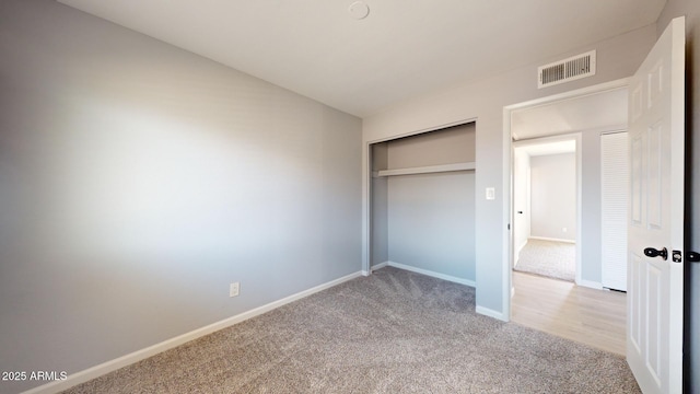 unfurnished bedroom featuring light carpet and a closet