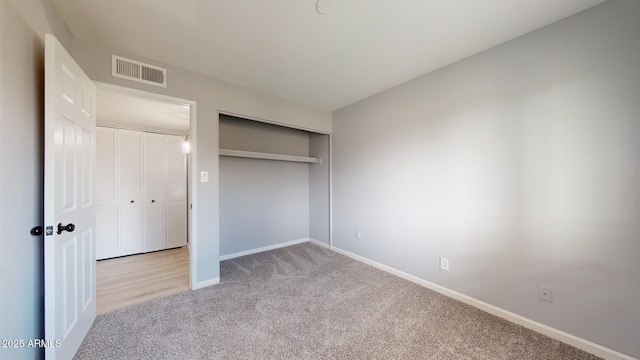 unfurnished bedroom featuring a closet and light carpet