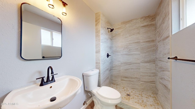 bathroom with sink, toilet, and tiled shower