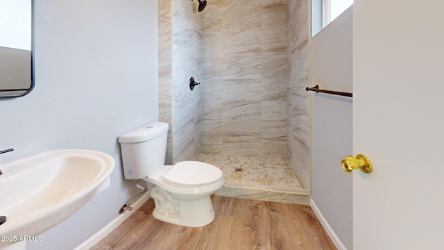 bathroom featuring hardwood / wood-style flooring, sink, a tile shower, and toilet