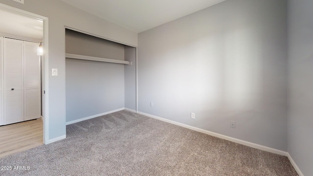 unfurnished bedroom with light colored carpet and a closet