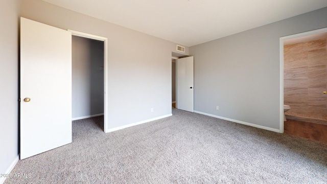 unfurnished bedroom with ensuite bathroom and carpet floors