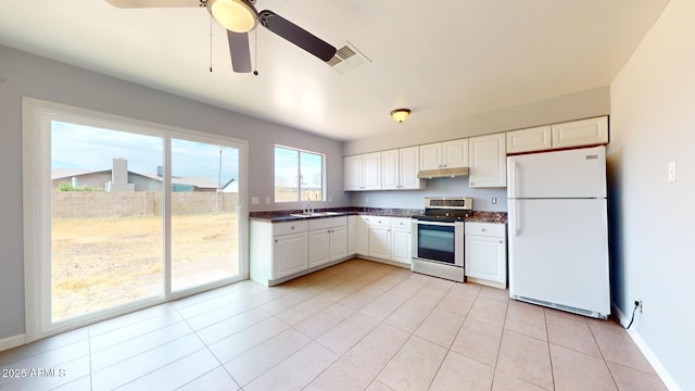 kitchen with sink, white cabinets, stainless steel electric range oven, light tile patterned flooring, and white fridge