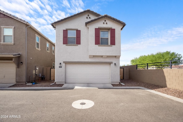 view of front of home featuring an attached garage, a tile roof, fence, and stucco siding