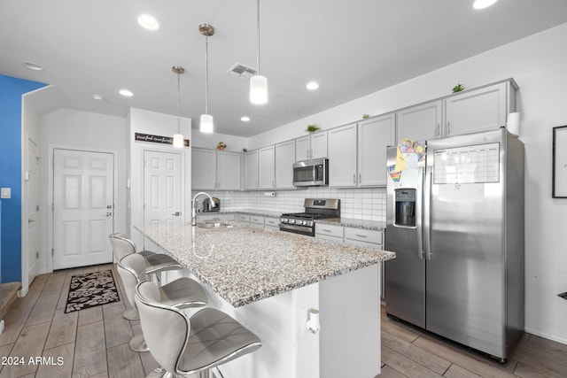 kitchen featuring visible vents, decorative backsplash, light stone counters, appliances with stainless steel finishes, and a sink