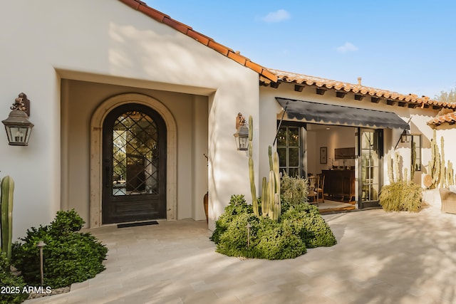 property entrance with a tiled roof and stucco siding