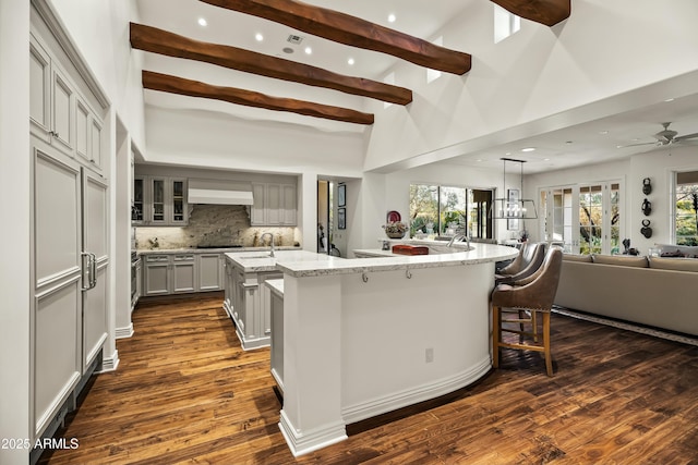 kitchen with a spacious island, open floor plan, gray cabinets, beam ceiling, and decorative backsplash