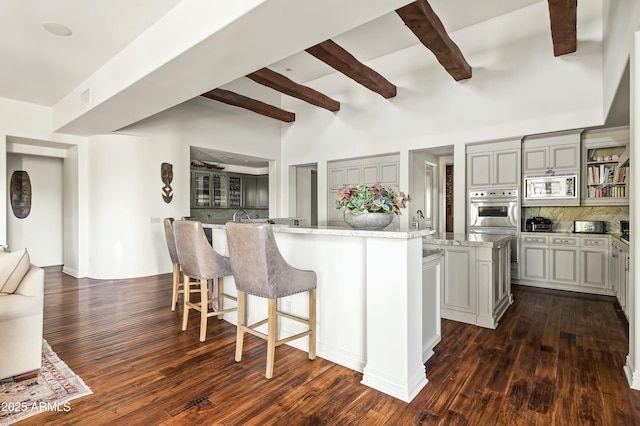 kitchen with stainless steel appliances, a kitchen island with sink, gray cabinetry, and tasteful backsplash