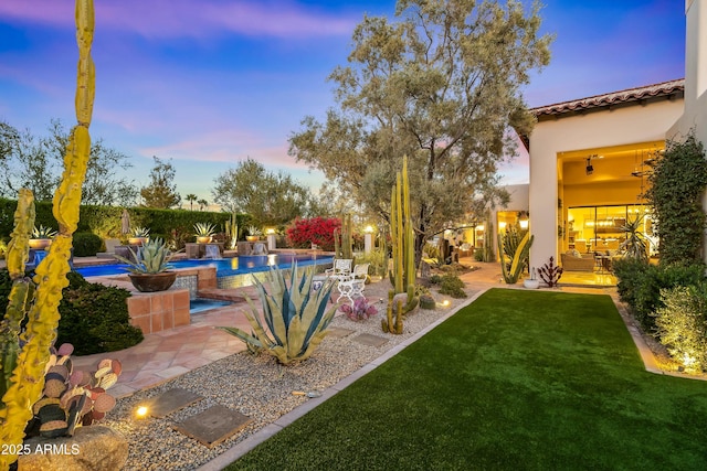 yard at dusk featuring fence, an outdoor pool, and a patio