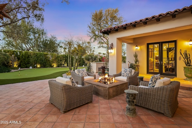 patio terrace at dusk featuring french doors and an outdoor living space with a fire pit