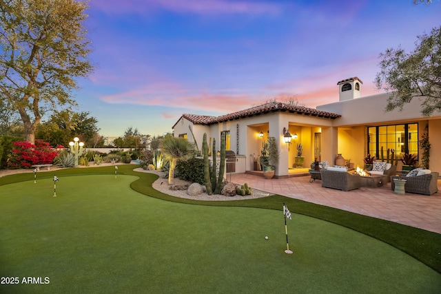 back of property at dusk with a patio, a fire pit, area for grilling, a tiled roof, and stucco siding