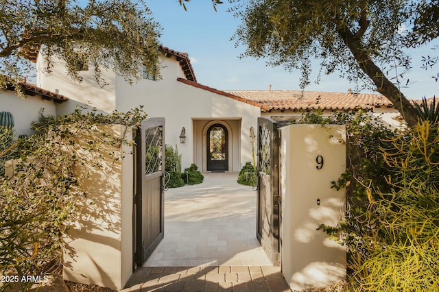 doorway to property with a tile roof and stucco siding