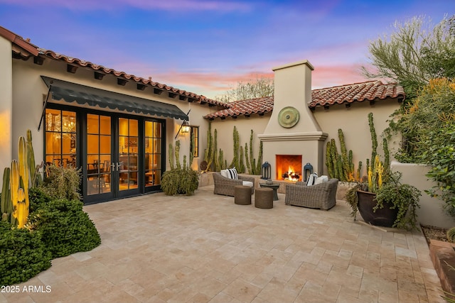 back of house with a patio, a tiled roof, french doors, stucco siding, and an outdoor living space with a fireplace