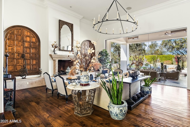 interior space featuring ceiling fan with notable chandelier, ornamental molding, a fireplace, and hardwood / wood-style flooring