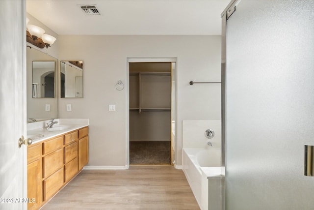 bathroom featuring a washtub, vanity, and hardwood / wood-style floors