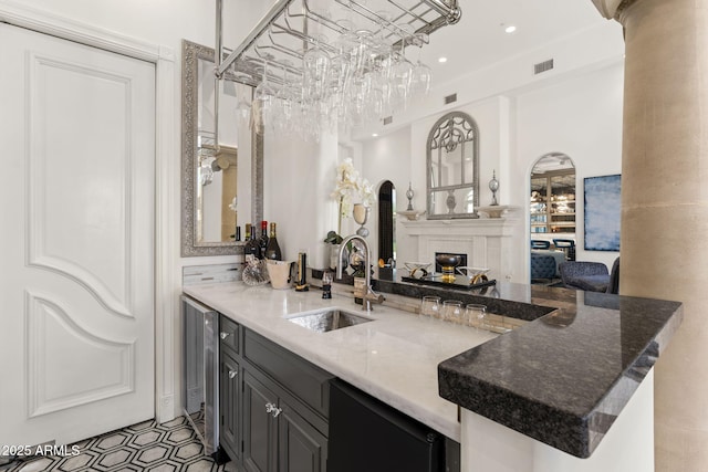 7475 E Gainey Ranch Rd Unit 22, Scottsdale, AZ 85258 - kitchen featuring decorative columns, a glass covered fireplace, a peninsula, wine cooler, and dark stone countertops