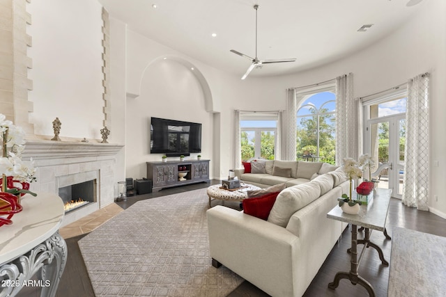 7475 E Gainey Ranch Rd Unit 22, Scottsdale, AZ 85258 - living area featuring ceiling fan, a tiled fireplace, recessed lighting, a towering ceiling, and wood finished floors