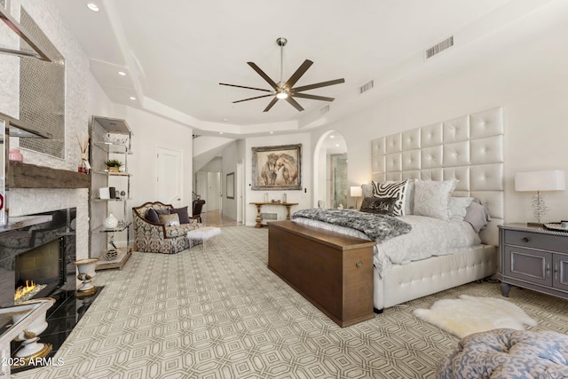 7475 E Gainey Ranch Rd Unit 22, Scottsdale, AZ 85258 - bedroom featuring a raised ceiling, arched walkways, a large fireplace, recessed lighting, and a ceiling fan