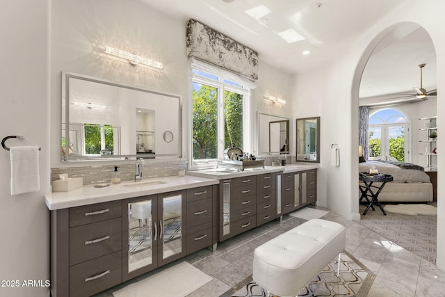 7475 E Gainey Ranch Rd Unit 22, Scottsdale, AZ 85258 - ensuite bathroom with vanity, decorative backsplash, ceiling fan, and a high ceiling