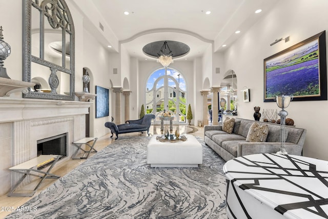 7475 E Gainey Ranch Rd Unit 22, Scottsdale, AZ 85258 - living room with arched walkways, decorative columns, a towering ceiling, recessed lighting, and a premium fireplace