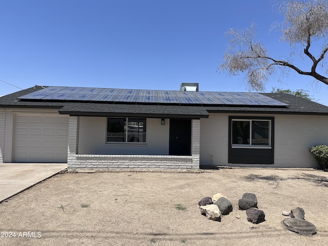 single story home featuring solar panels and a garage