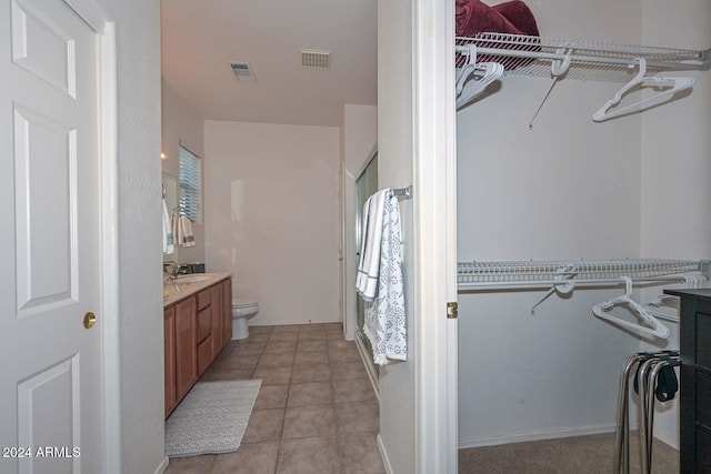 bathroom with tile patterned flooring, vanity, toilet, and a shower with shower door