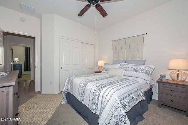 bedroom with ceiling fan, a closet, and light colored carpet