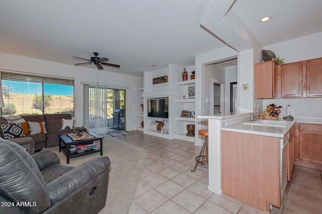 kitchen with built in shelves, ceiling fan, sink, kitchen peninsula, and a breakfast bar