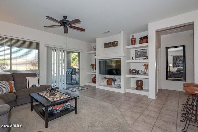 living room with ceiling fan, built in features, and light tile patterned floors