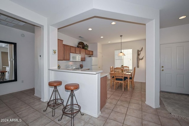 kitchen with kitchen peninsula, light tile patterned floors, decorative light fixtures, and white appliances