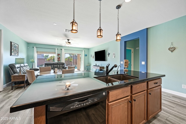 kitchen featuring ceiling fan, a kitchen island with sink, sink, dishwasher, and light hardwood / wood-style floors