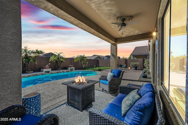 patio terrace at dusk featuring a fenced in pool and an outdoor living space with a fire pit