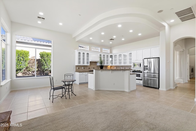 5892 E Evening Glow Dr, Scottsdale, AZ 85266 - kitchen featuring arched walkways, dark countertops, appliances with stainless steel finishes, glass insert cabinets, and white cabinetry