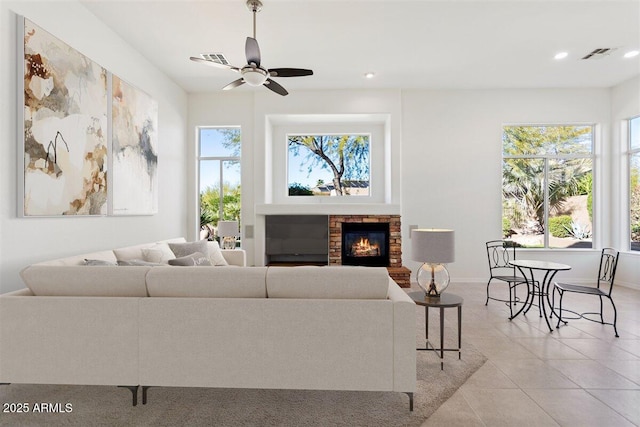 living room featuring light tile patterned floors, a glass covered fireplace, visible vents, and a healthy amount of sunlight