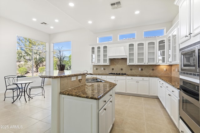 5892 E Evening Glow Dr, Scottsdale, AZ 85266 - kitchen featuring white cabinets, glass insert cabinets, dark stone countertops, custom exhaust hood, and stainless steel appliances
