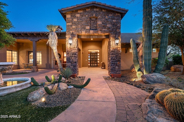 exterior entry at dusk featuring a patio area