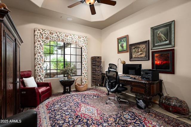 home office featuring a tray ceiling and ceiling fan